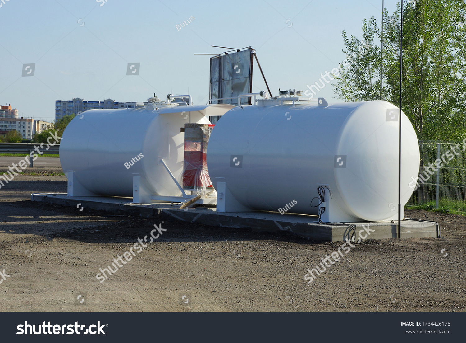 stock-photo-two-large-industrial-iron-white-barrels-at-a-gas-station-stand-on-gray-asphalt-by-the-road-1734426176
